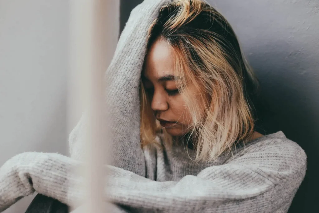 worried young woman indoors with head in hands
