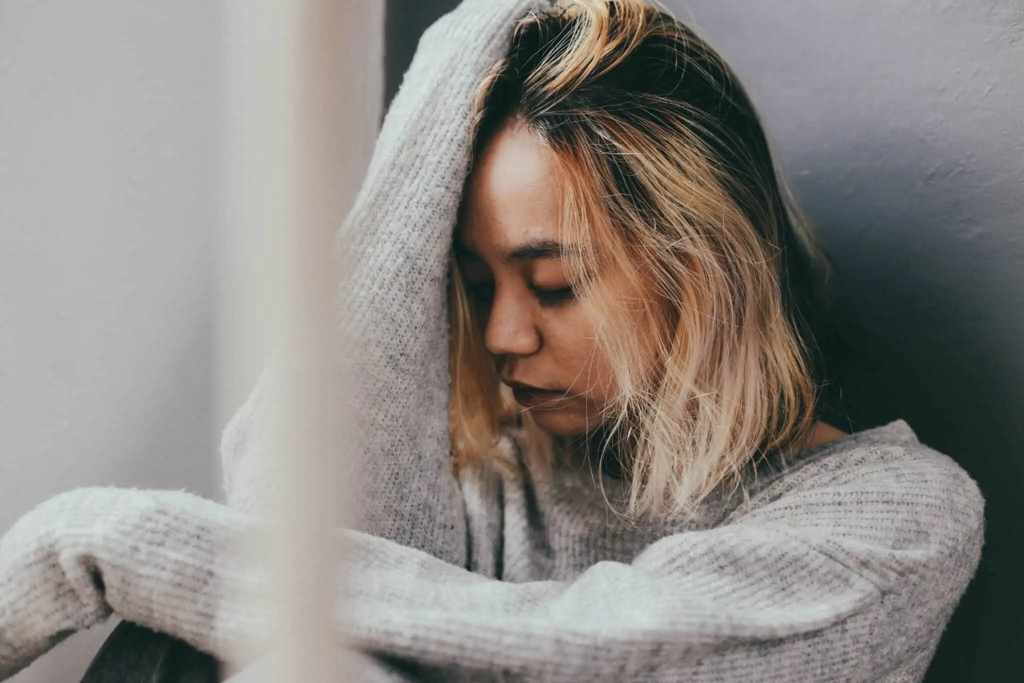 worried young woman indoors with head in hands